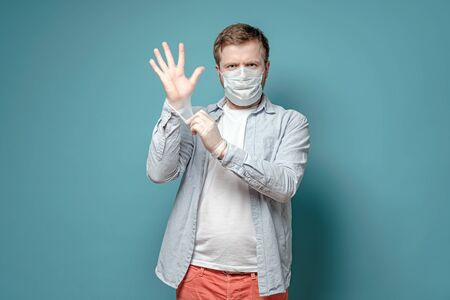 Serious man in a medical mask, puts on latex gloves, to protect against a dangerous virus. Health and safety concept.の写真素材