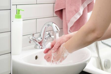 Washing hands with liquid soap under running water to protect against a dangerous virus. Health concept. Close-up.の写真素材