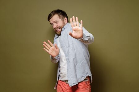 Frightened man is afraid of getting the virus, he makes a stop gesture with hands and looks with disgust. Health concept.の写真素材