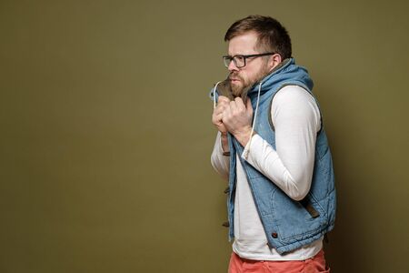 Attractive bearded man wearing glasses is very froze, he takes refuge in bewilderment and perplexity in a vest. Copy space.の写真素材