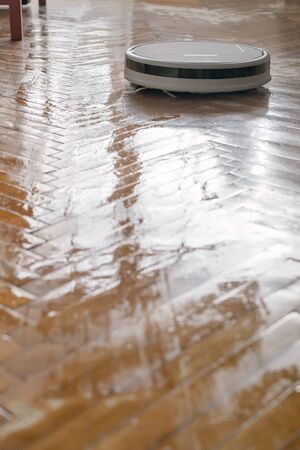 Washing robot vacuum cleaner makes wet cleaning of a parquet floor. Indispensable help in the household.の写真素材