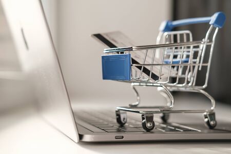 A mini trolley from a supermarket stands on a laptop keyboard. The concept of online shopping while quarantineの写真素材