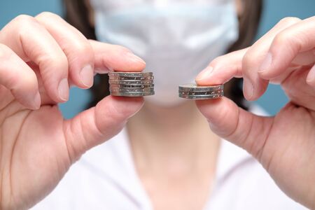 Hands compare piles of coins of different sizes, pointing to a worsening financial situation due to virus epidemic and pandemic.の写真素材