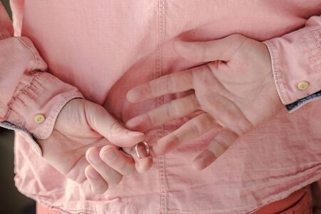 Hands of a man who took off a golden, wedding ring behind back, having come to his mistress. Close-up.の写真素材