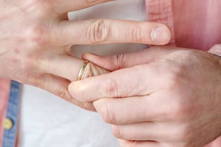 Man removes a gold wedding ring from his finger. Concept of family quarrel, divorce or betrayal.の写真素材