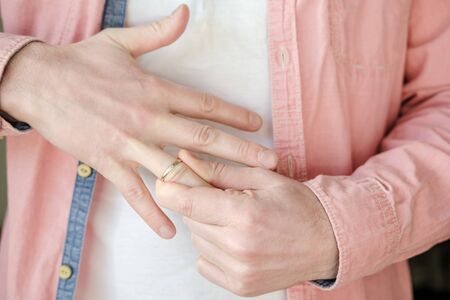 Man takes off a golden, engagement ring from his finger. Concept of family quarrel, divorce or treason. Close-up.の写真素材