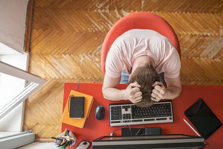 Man works remotely at home on a computer and he experiences stress. Concept of self-isolation during a pandemic. Modern lifestyle.の写真素材