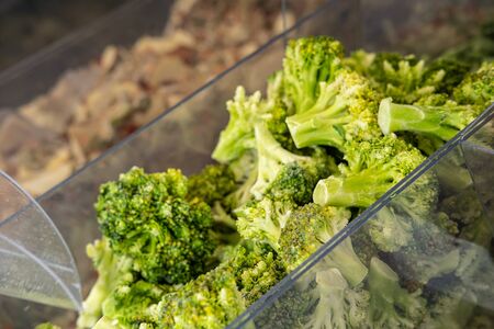 Frozen broccoli in a transparent container, on a counter in a store, on a blurred background.の写真素材