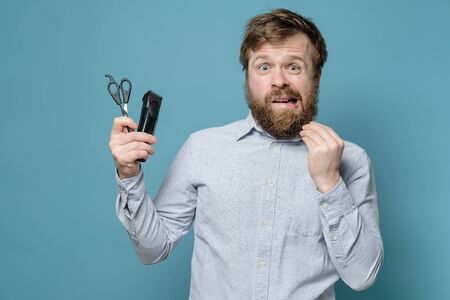 Shaggy man is alarmed because he need to cut himself with scissors and trimmer during quarantine.の写真素材