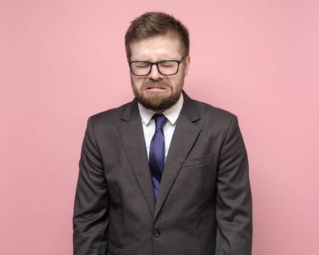 Caucasian man in glasses and a suit is sobbing, he is upset and experiencing stress. Concept of psychological health.の写真素材