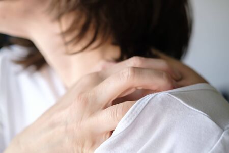Female hand scratch itchy skin on his shoulder.の写真素材