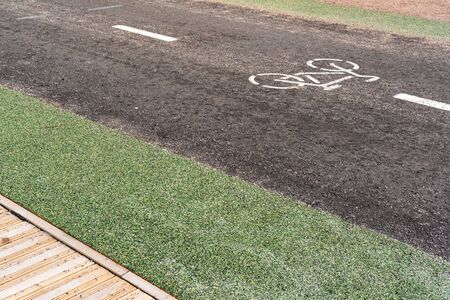 Bicycle path with a symbol of a bicycle, next to a pedestrian area made of wood, outdoors. Sports and recreation, active lifestyle.の写真素材