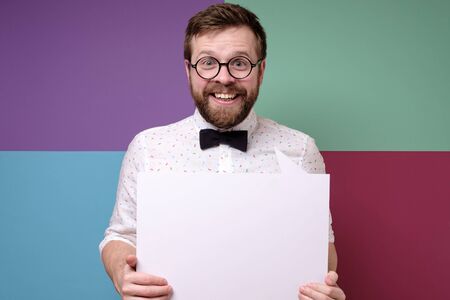 Cute, weird salesman is holding an empty white board with copy space and is smiling friendly. Seasonal discounts, advertising.の写真素材