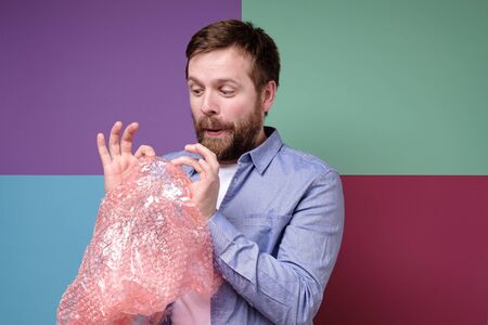 Young, funny man popping a plastic wrap as a therapy and calms down after experiencing stress.の写真素材