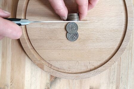 Hands cut dollar coins with a knife, separating them like pieces of food. Concept of taxes, fraud or...