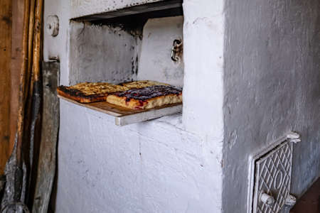 Pies cooked in a traditional Russian oven, on a cutting board, next to the wall, there are old kitchen utensils, in a village house.の写真素材