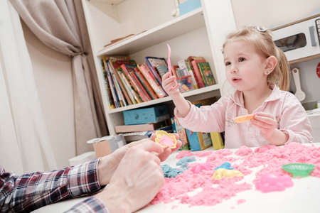 Daughter with father is playing with kinetic sand and toys. Concept development in children fine motor skills and creative.の写真素材