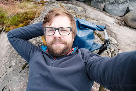 Cute, happy tourist takes a selfie while lying on the rocky surface. Leisure activities and lifestyle.の写真素材