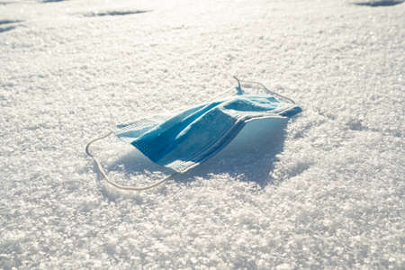Used medical mask thrown out into the snow. Concept of caring for the environment. Copy space.の写真素材