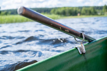 Metal oarlock holding an oar in a boat, against the background of a lake on a summer day.の写真素材