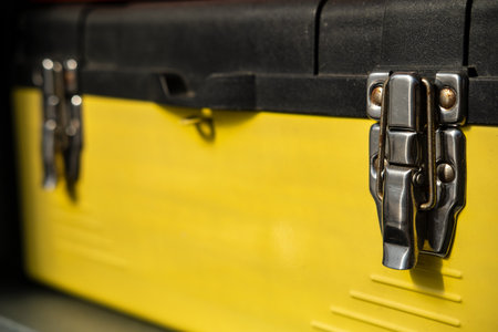 Yellow-black toolbox is closed with two metal locks.の写真素材