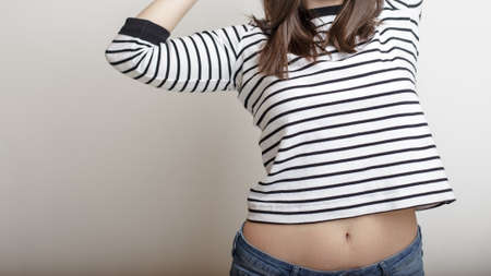 Confident girl in blue jeans and a striped sweater, raised her arms and extended her beautiful belly...