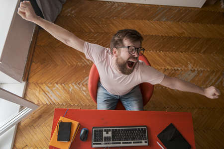 The man is tired and yawns while working with a computer at home, remotely. Modern lifestyle concept.の写真素材