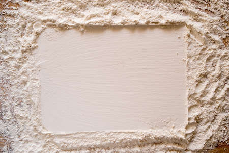 Flour sprinkled on a wooden table, with a smooth rectangular imprint for the inscription. Copy space.の写真素材