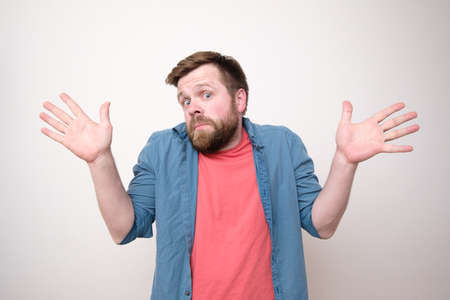 Surprised bearded man in bewilderment, he is innocent and makes a gesture with hands, open palms, looks at the camera.の写真素材