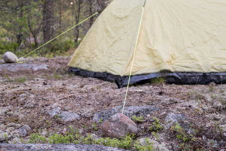 Tent on the rocks, with gorges tied to stones for safety in strong winds. Leisure activities and lifestyle.の写真素材