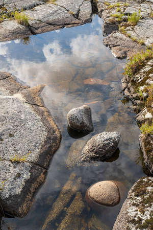 Clear clear water with a reflection of blue sky and clouds in the rock.の写真素材