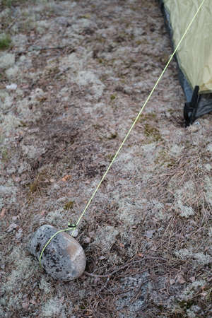 Rope from the tent is tied to a stones for safety in strong winds. Close-up.の写真素材