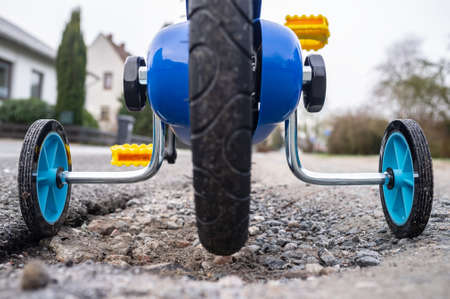 Children bike with small wheels on the sides for a safe ride on the streets of a provincial town. Close-up.の写真素材