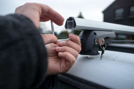 Hands with a screwdriver installs attachments for the trunk or cargo box on the roof of the car.の写真素材
