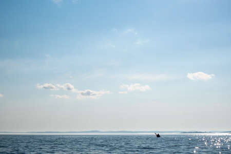 Silhouette of a kayak with tourists floating on the lake against the horizon. Active rest. Beautiful landscape.の写真素材