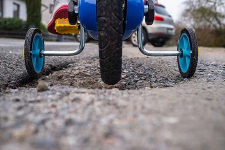Children bike with small wheels on the sides for a safe ride, against the background of the car. Close-up.の写真素材