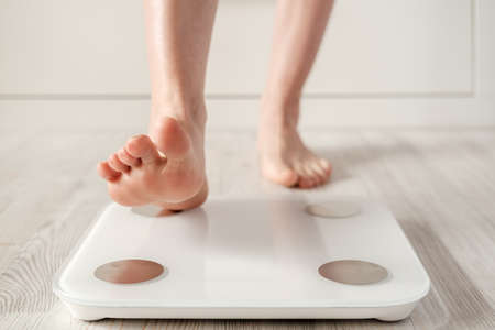 Woman foot takes a step onto a smart scale that makes bioelectric impedance analysis, BIA, body fat measurements.の写真素材