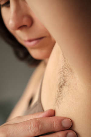 Hairy, unshaven female armpits on a blurred background of a female face. Concept of body positive and the adoption of its naturalness.の写真素材