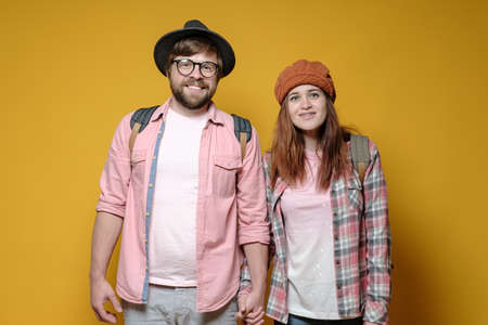Satisfied smiling tourists man and woman with backpacks. Yellow background.の写真素材