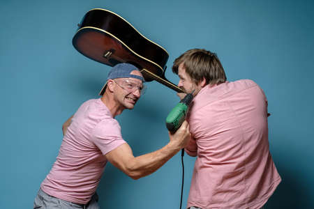 Musician and construction worker, they started a fight over the noise, one threatens with a drill, the other with a guitar.の写真素材