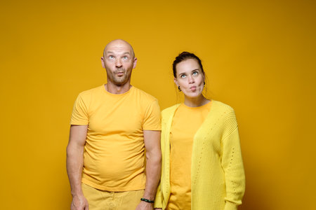 Strange man and woman in yellow robes, made stupid faces. Bright background.の写真素材