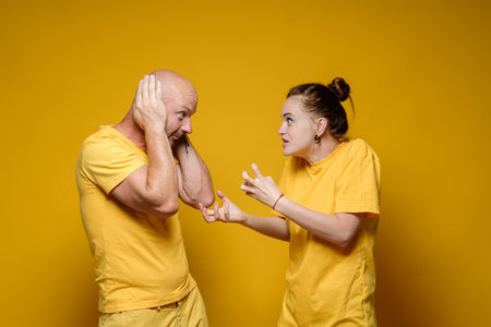 Abuse. Furious woman screams and scolds the man who, in fear, covered his ears with his hands. Domestic violence concept.の写真素材