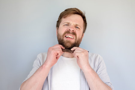 Man holding double chin in his hands, he is very upset about obesity and overweight. Concept of proper nutrition and lifestyle.の写真素材