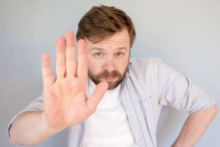 Calm, confident man makes a stop gesture, palm forward and looks seriously into the camera.の写真素材