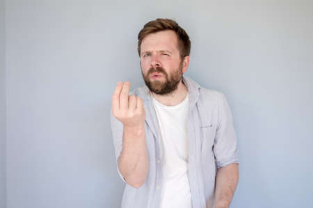 Bearded Caucasian man in a shirt argues, he is trying to prove something to someone, looks with bewilderment and shows a hand gesture.の写真素材