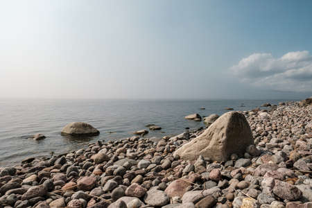 Magnificent landscape. Clean, calm sea and the rocky shore, skyline, with blue sky and white clouds in the summer day.の写真素材