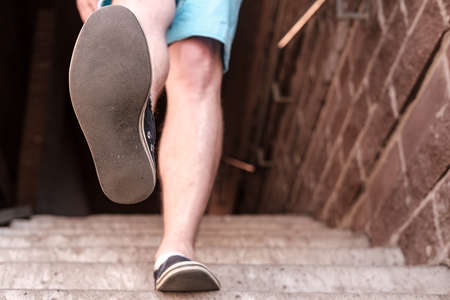 Men feet in casual shoes walk down the stone steps on a summer day. Bottom view.の写真素材