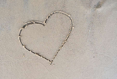 Heart symbol painted on a sandy river bank on a warm summer day. Vacation romance. Lifestyle. Copy space. Top view.の写真素材