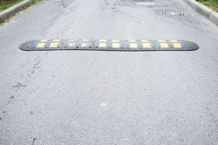 Yellow and black speed bumps on the asphalt road. Obstacle in the path of vehicles to reduce the speed and safety of pedestrians.の写真素材