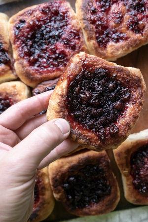 Hand holds a delicious, appetizing homemade pie with berry filling, cooked in a Russian oven. Hearty, hot snack. Traditional cuisine.の写真素材